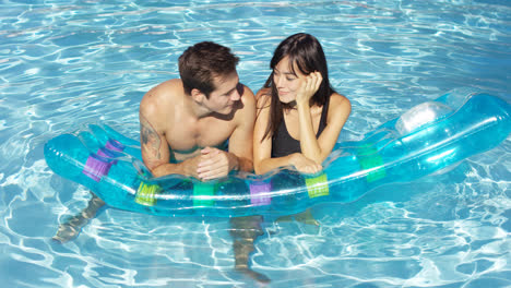 Woman-touching-face-of-man-floating-in-pool