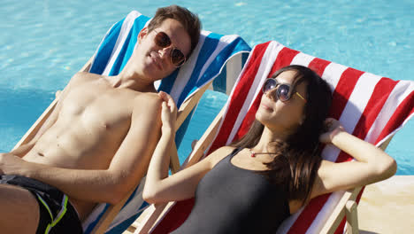 Young-couple-relaxing-at-a-resort-swimming-pool