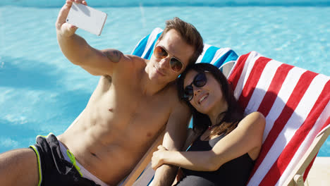 Man-taking-picture-of-himself-with-wife-at-pool