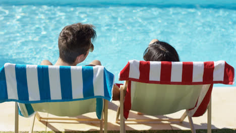 Couple-relaxing-in-colorful-deck-chairs-poolside