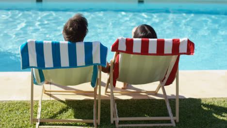Couple-relaxing-in-colorful-deck-chairs-poolside