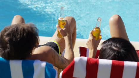 Young-couple-enjoying-a-beer-at-the-pool