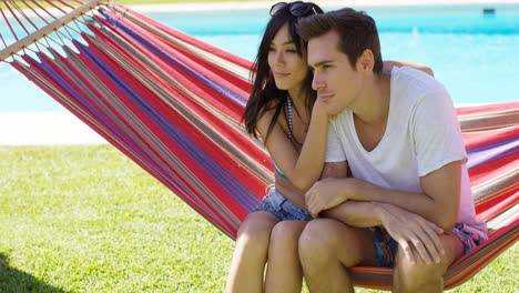 Affectionate-young-couple-sitting-on-a-hammock