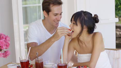 Man-feeding-his-wife-fruit-at-breakfast