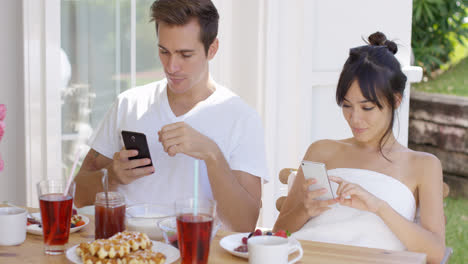 Abgelenktes-Paar,-Das-Smartphones-Am-Tisch-Benutzt