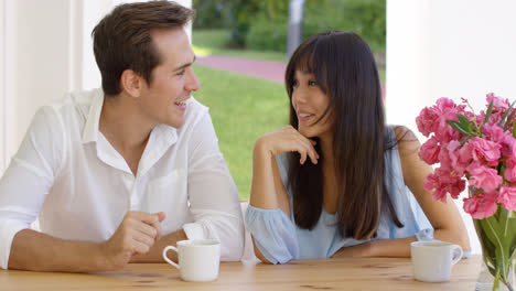 Laughing-young-adult-couple-sitting-at-table