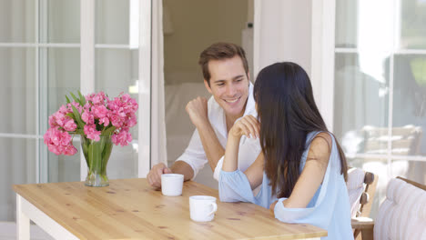 Joyful-mixed-adult-couple-sitting-at-table