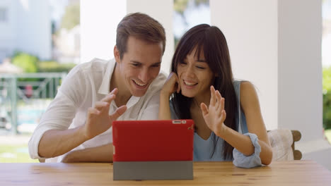 Man-and-woman-waving-at-their-tablet-computer