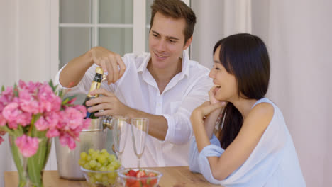 Happy-young-couple-opening-champagne-to-drink