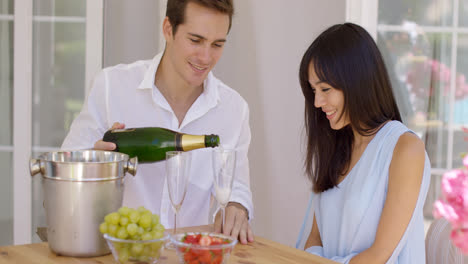 Smiling-young-couple-pouring-champagne-to-drink