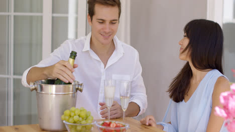 Smiling-young-couple-pouring-champagne-to-drink