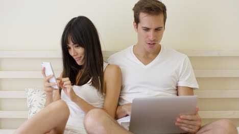 Young-mixed-couple-sitting-in-bed-with-laptop