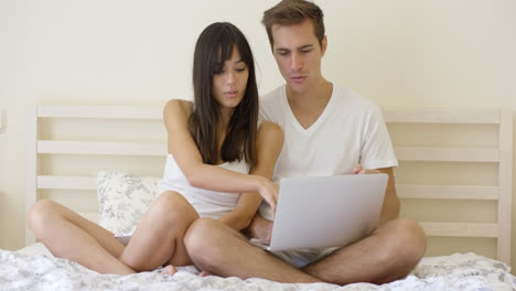 Woman-talking-to-man-using-laptop-while-in-bed