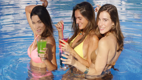 Drei-Wunderschöne-Frauen-Im-Pool-Mit-Bunten-Drinks