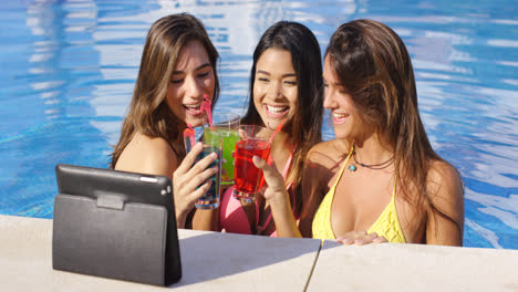 Three-bikini-clad-friends-toasting-pool-side