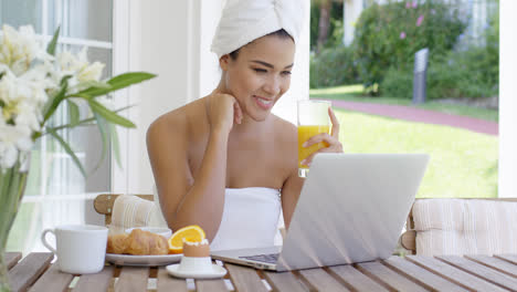 Mujer-Joven-Usando-Una-Computadora-Portátil-Mientras-Desayuna