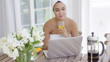 Woman-in-towel-with-laptop-having-breakfast