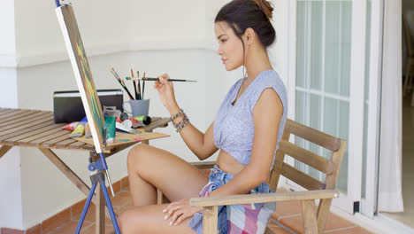 Young-woman-sitting-painting-on-her-patio