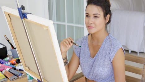 Attractive-young-woman-artist-painting-a-canvas