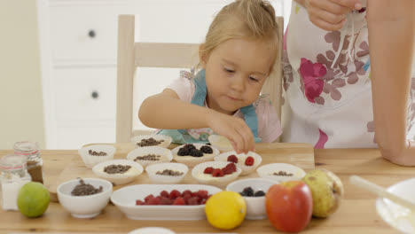 Little-girl-placing-berries-on-muffins