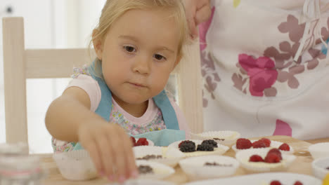 Child-and-woman-preparing-muffins-on-table