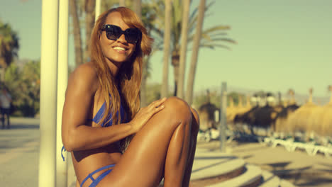 Glückliches-Afrikanisches-Mädchen-Im-Bikini-Sitzt-Auf-Strandbank