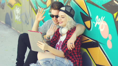 Fun-young-couple-waving-at-a-tablet-pc