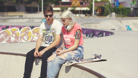 Young-couple-of-skateboarders-sitting-chatting