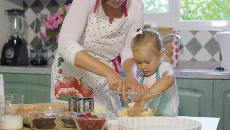 Cute-little-girl-helping-her-mother-bake