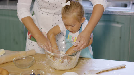 Cute-little-girl-helping-Mum-knead-the-dough