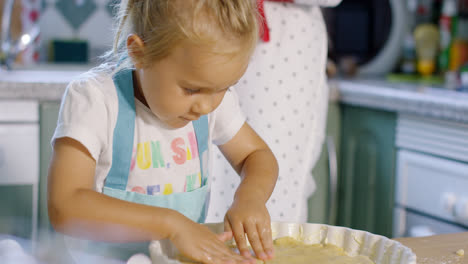 Adorable-little-girl-baking-a-tart-with-her-mother