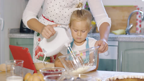 Little-girl-watching-her-mother-whisking-cream