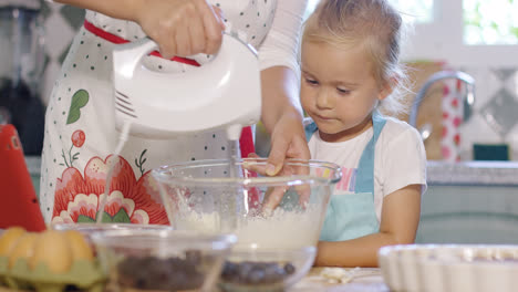 Little-girl-watching-her-mother-whisk-cream