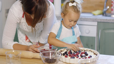 Young-mother-watching-her-little-daughter-baking