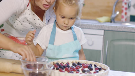 Mutter-Und-Tochter-Geben-Frische-Beeren-In-Einen-Kuchen