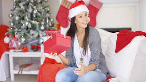 Curious-young-woman-shaking-a-Christmas-gift