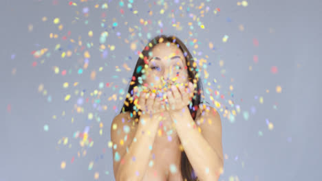 Young-woman-blowing-colorful-New-Year-confetti