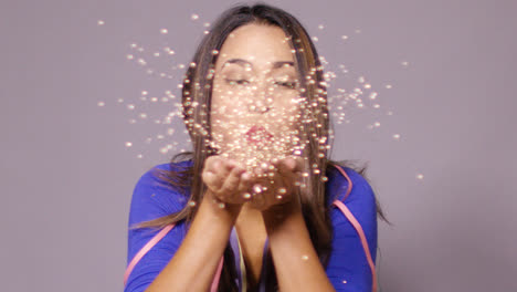 Fun-young-woman-blowing-a-spray-of-confetti