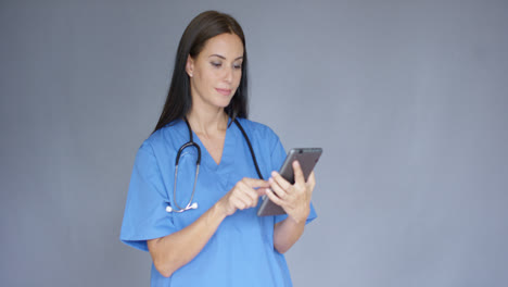 Young-female-doctor-in-scrubs-using-a-tablet