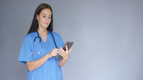 Young-female-doctor-in-scrubs-using-a-tablet