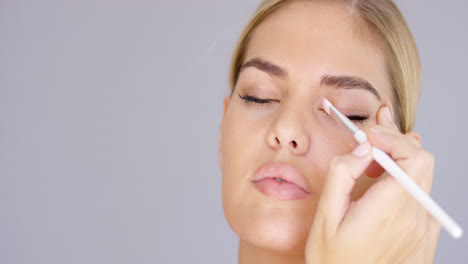 Young-woman-applying-eye-makeup-to-her-eyelid