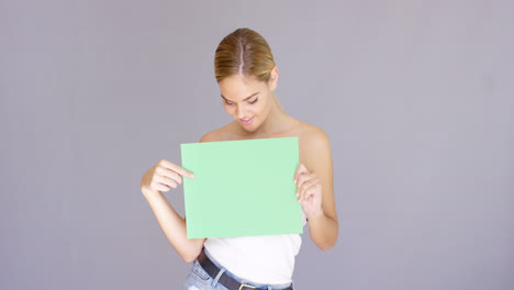 Attractive-blond-woman-holding-a-blank-green-sign