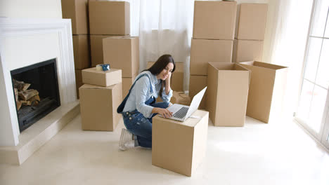 Young-woman-using-a-laptop-on-a-cardboard-box