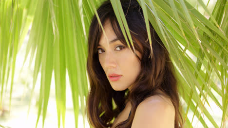 Shy-young-woman-in-shade-of-palm-leaves
