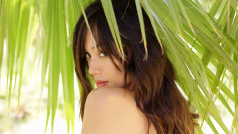 Shy-young-woman-in-shade-of-palm-leaves