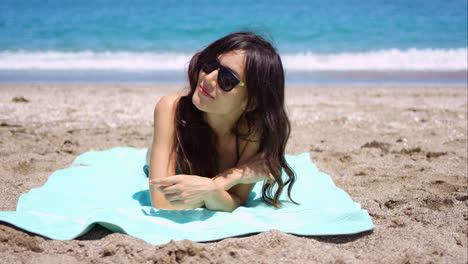 Pretty-woman-in-sunglasses-sunbathing-on-a-beach