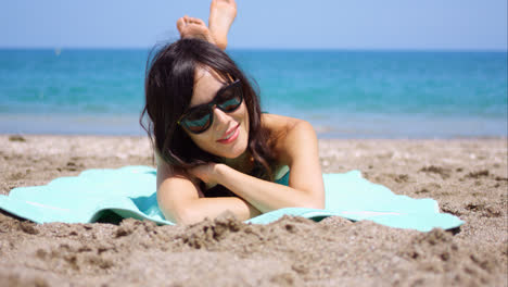 Pretty-woman-in-sunglasses-sunbathing-on-a-beach