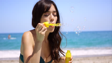 Pretty-young-woman-blowing-bubbles-on-a-beach