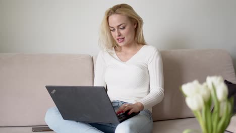 Glad-female-using-laptop-on-sofa