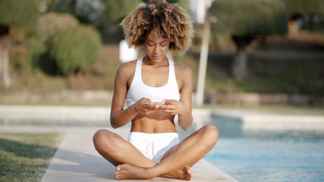 Woman-Using-Her-Phone-While-Sitting-At-Poolside